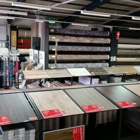 Große Auswahl an Bodenbelägen und Laminat in einem Baumarkt mit verschiedenen Mustern.