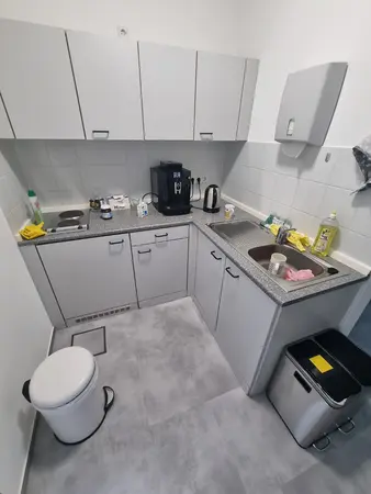 Kleine Büroküche mit Spüle, Kaffeemaschine, Wasserkocher und Herdplatte
