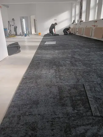 Handwerker verlegen Teppichfliesen im Büro, Bodenbelag-Installation im Raum