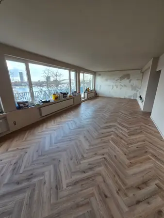 Renovierter Wohnraum mit Fischgrätparkett, großen Fenstern und Flussblick