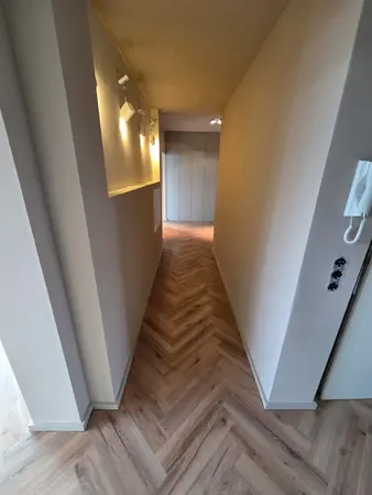Schmaler Wohnungsflur mit Fischgrätparkett, Wandleuchten und Einbauschrank