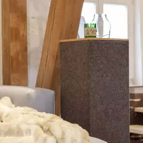 Gemütliches Wohnzimmer mit moderner Holztreppe, Sofa, Kuscheldecke und Dekoration.